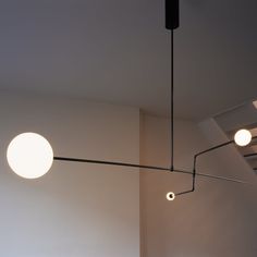 three lights hanging from the ceiling in a room with white walls and black metal fixtures