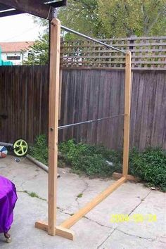 a backyard with a wooden structure and purple cloth on the ground in front of it