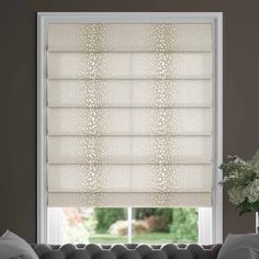 a living room with a couch and window covered in white roman blind shades on the windowsill