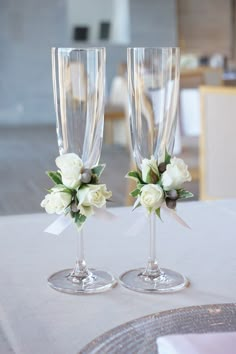 two champagne flutes with flowers on them sitting on a table