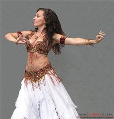 a woman in a belly dance outfit with her arms outstretched and hands out to the side