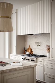 a kitchen with white cabinets and marble counter tops