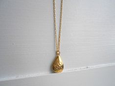 "A tiny golden teardrop locket hangs from a gold chain. Please select a length from the drop-down box. The locket measures 3/4\" x 3/8\". *We do not personalize nor insert pictures. The locket and chain are gold plated over brass, so it's recommended removing before showering, swimming, etc. to keep jewelry looking like new." Gold Teardrop Charm Necklaces For Wedding, Gold Teardrop Charm Necklace For Wedding, Gold Drop Charm Necklaces For Gift, Gold Teardrop Pendant For Wedding, Gold Drop Necklace For Anniversary, Gold Teardrop Charm Necklace For Gift, Gold Teardrop Pendant Charm Necklace As Gift, Gold Drop Necklace For Gift, Vintage Drop Necklace For Gift