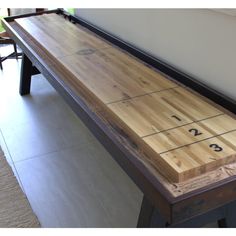 a wooden shuffle board sitting on top of a floor next to a table with numbers