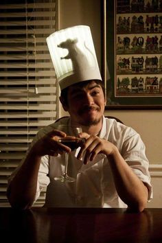 a man sitting at a table wearing a chef's hat