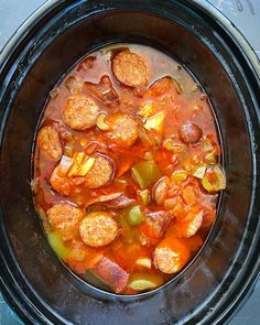 there is a stew in the crock pot with hot dogs and peppers on top