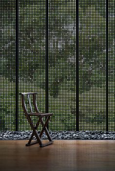 a wooden chair sitting in front of a screen wall