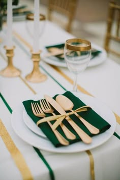 the table is set with gold and green place settings, silverware, and napkins