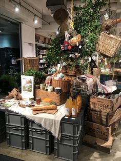 a table with baskets and bottles on it in a room filled with plants, food and other items