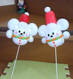 two white balloons shaped like bears with hats on their heads and noses are sitting on top of each other