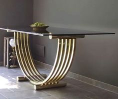 a glass table with gold lines on it in front of a gray wall and tile floor