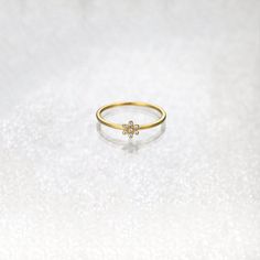 a gold ring with a flower on the middle, sitting on a white tablecloth