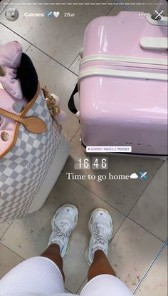 a person standing next to a pink and white suitcase with the words time to go home written on it