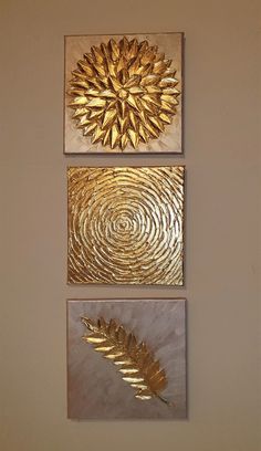 three gold metal artwork pieces hanging on the wall