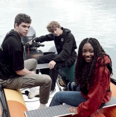 three people sitting on a boat in the water