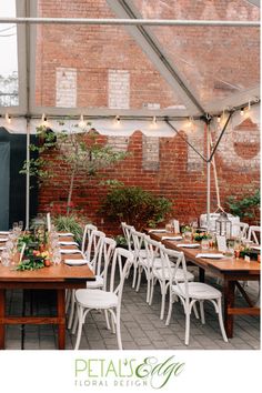 an outdoor dining area with white chairs and wooden tables set up for a formal function