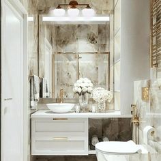 a white toilet sitting next to a sink in a bathroom under a mirror above it