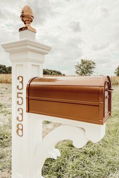 a mailbox in the middle of a field with a statue on top of it