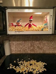 two elfs are in the microwave with popcorn