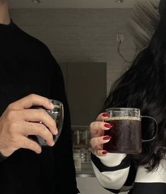 a man and woman holding mugs in their hands