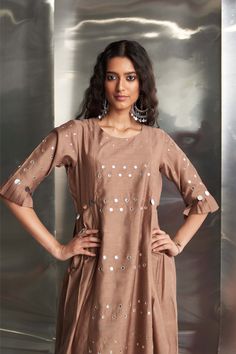 This Chanderi kurta in a beautiful ginger hue features mirror work on the front panel and sleeves, with stylish pleated sleeves adding flair. Paired with a Chanderi dupatta embroidered with mirror work along the borders, and wide-flare cotton palazzos highlighted with mirrors, this ensemble ensures a stylish and coordinated look. The bottom is elasticated with a drawstring for comfort. Slub Silk Anarkali Set With Mirror Work, Anarkali Slub Silk Palazzo Set With Mirror Work, Slub Silk Palazzo Set With Mirror Work For Festivals, Mirror Work Slub Silk Palazzo Set For Festivals, Bollywood Style Slub Silk Palazzo Set With Mirror Work, Chanderi Sharara With Mirror Work And Straight Kurta, Designer Anarkali Set With Mirror Work, Straight Kurta, Designer Slub Silk Sets With Mirror Work, Mirror Work Slub Silk Sets