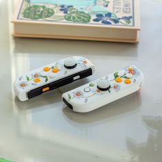 two video game controllers sitting on top of a table next to a book and pen