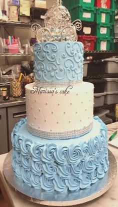 a three tiered cake with blue frosting and a tiara on top that reads, princess's cafe