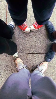 four people standing in a circle wearing red and blue shoes