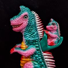 two toy dinosaurs riding on top of each other