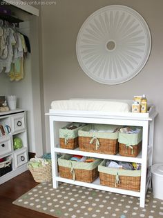 a baby's nursery room with white furniture and baskets on the shelf next to it