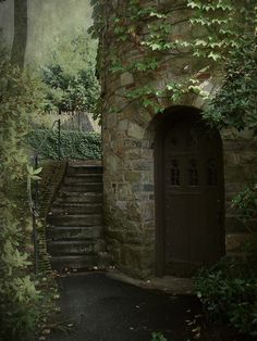 an old stone building with ivy growing on it's side and stairs leading up to the door