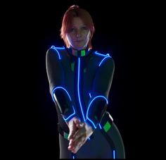 a woman in a body suit with neon lights on her chest and arms outstretched, looking at the camera