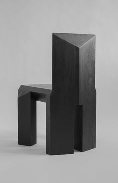 a black chair sitting on top of a white floor next to a wooden block structure