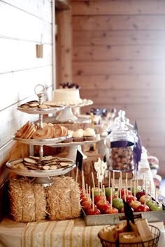 an assortment of desserts and pastries are displayed on a buffet table with straw bales