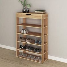 a wooden shoe rack with several pairs of shoes on it and a plant in the corner