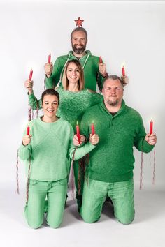 a group of people in matching green outfits holding candles and smiling at the camera while standing next to each other