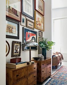 a living room with pictures on the wall and a dresser in front of an open door