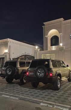 two jeeps parked in front of a building at night