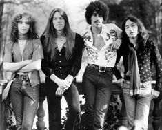 the rolling stones posing for a photo in front of a fence with their arms crossed