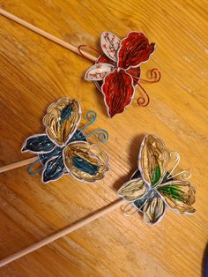 three paper butterflies sitting on top of a wooden table