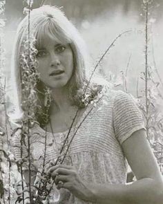 black and white photograph of a woman standing in tall grass with her hands on her hips