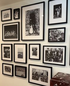 black and white photographs are hung on the wall above a trunk in front of a suitcase