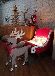 a wooden sleigh with reindeers on it in front of a christmas tree