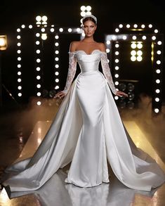 a woman in a white wedding dress standing on a stage with lights behind her and wearing a tiara