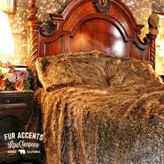 a fur covered bed in a bedroom with floral wallpaper and wooden headboard,