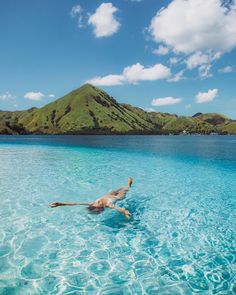 a person floating in the water on top of a body of water with mountains in the background