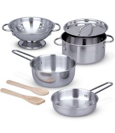 four stainless steel pots and pans with wooden utensils on a white background