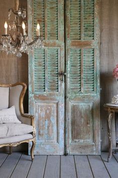 an old wooden door in a room with two chairs and a chandelier hanging from the ceiling