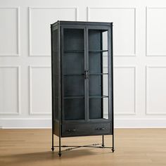 a tall black cabinet with glass doors on the front and bottom shelves, sitting on a hard wood floor