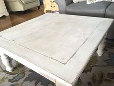 a white coffee table sitting on top of a wooden floor next to a gray couch